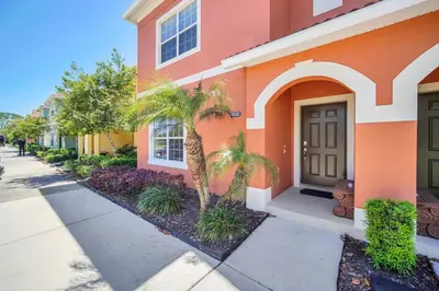a orange building with palm trees in front of it at Ev8940 - Magic Palms Retreat in Kissimmee