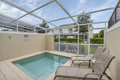 a patio with a swimming pool and chairs at Ev1445 - The Palm Retreat in Orlando
