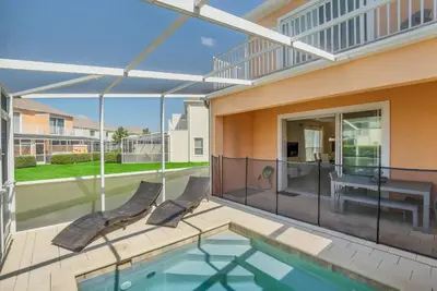 a patio with a pool and two chairs and a table at Ev1511 - The Serenity Villa in Orlando