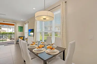 a dining room with a table and white chairs at Ev1511 - The Serenity Villa in Orlando