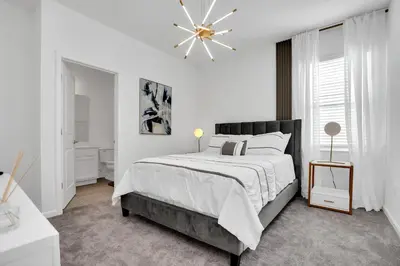 a white bedroom with a large bed and a chandelier at Ev2395 - Grand Haven Retreat in Kissimmee