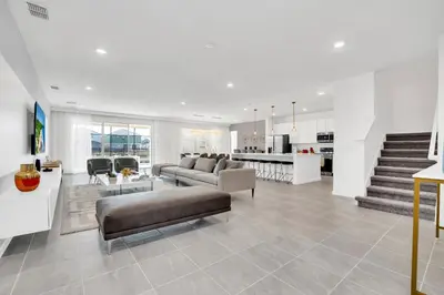 a living room with couches and a kitchen and staircase at Ev2395 - Grand Haven Retreat in Kissimmee