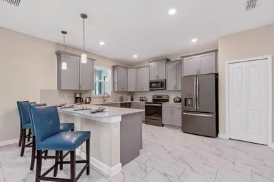 a large kitchen with white cabinets and blue chairs at Ev2707 - Magic Getaway Villa in Kissimmee