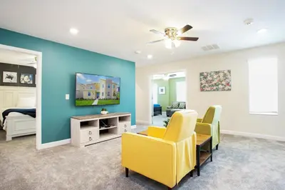 a living room with yellow chairs and a blue wall at Ev2709 - Enchanted Retreat Villa in Kissimmee