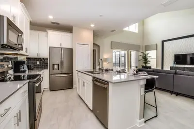 a large kitchen with white cabinets and stainless steel appliances at Ev2755Book - Golden Horizon Villa in Kissimmee