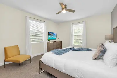 a white bedroom with a bed and a chair at Ev2775 - Majestic Escape Villa in Kissimmee