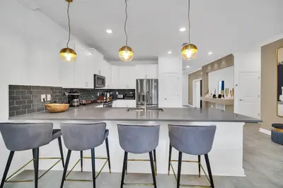 a kitchen with a large island with three bar stools at Ev2900 - Sunset Cove Retreat in Kissimmee