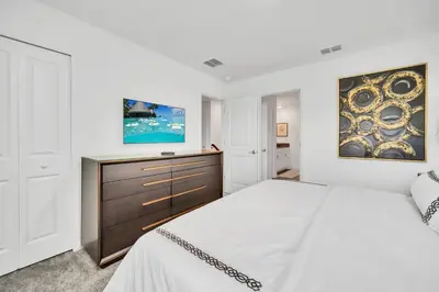 a white bedroom with a large bed and a dresser at Ev2989 - Serenity Palms Villa in Kissimmee