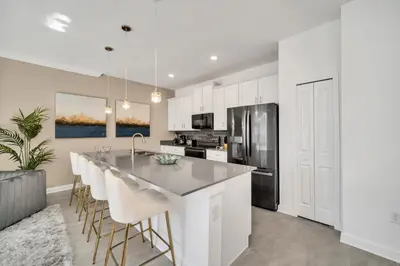 a kitchen with white cabinets and a kitchen island with bar stools at Ev3007 - Lakeside Escape Villa in Kissimmee
