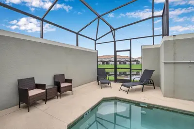 a patio with chairs and a swimming pool at Ev3097 - Lakeside Serenity Villa in Kissimmee