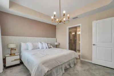 a bedroom with a large white bed and a chandelier at Ev101 - The Luxe Loft in Kissimmee