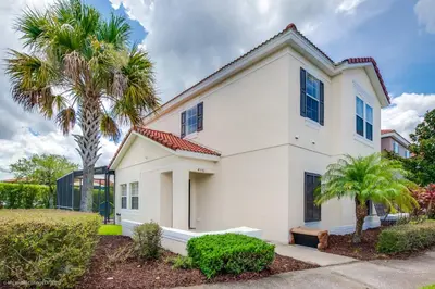 a white house with a palm tree at Ev4550 - Bella Vista Haven in Kissimmee