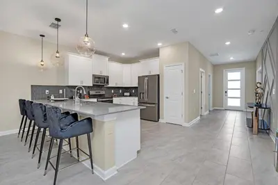 a kitchen with white cabinets and a island with bar stools at Ev4568 - Storey Oasis in Kissimmee