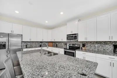 a kitchen with white cabinets and a granite counter top at Ev4710 - Regal Villa in Kissimmee