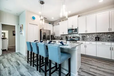 a kitchen with white cabinets and blue bar stools at Ev4755 - Tranquil Haven Villa in Kissimmee