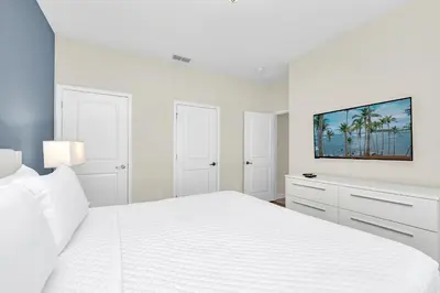 a white bedroom with a white bed and a tv at Ev4876 - Charming Palms Villa in Kissimmee