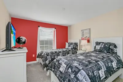 two beds in a bedroom with red walls and a tv at Ev4886 - Palm Haven Escape in Kissimmee