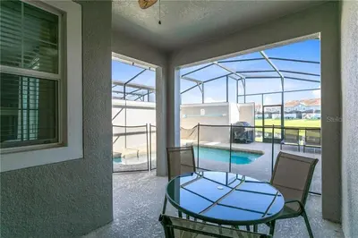 a glass table and chairs on a balcony with a pool at Ev4887 - Golden Palms Retreat in Kissimmee
