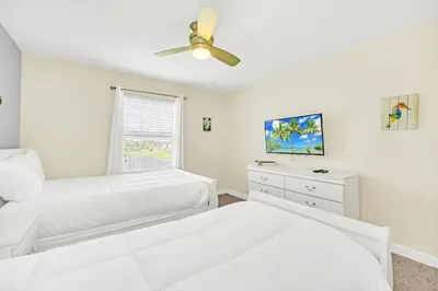 a white bedroom with a bed and a ceiling fan at Ev4927 - Beautiful Storey Lake in Kissimmee