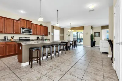 a large kitchen with wooden cabinets and bar stools at Ev8927 - Paradise Dream Retreat in Kissimmee