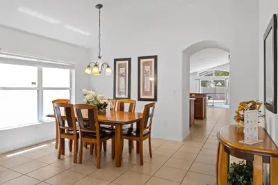 a dining room with a wooden table and chairs at Casa 4Q c/ Piscina & Spa no Veranda Palms in Kissimmee