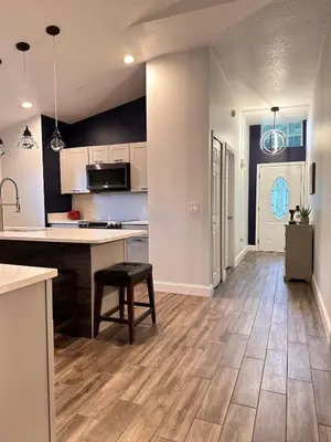 an open kitchen and living room with wooden floors at Beautiful 5BR home near Disney with private pool, large yard & BBQ in Orlando