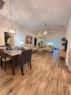 a dining room and living room with a table and chairs at Beautiful 5BR home near Disney with private pool, large yard & BBQ in Orlando