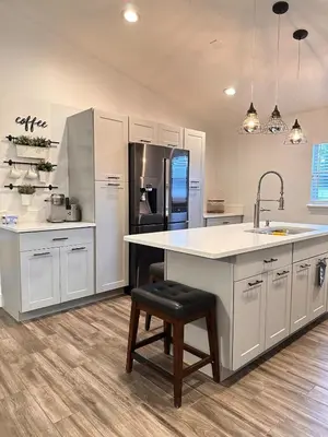 a kitchen with white cabinets and a counter and a refrigerator at Beautiful 5BR home near Disney with private pool, large yard & BBQ in Orlando