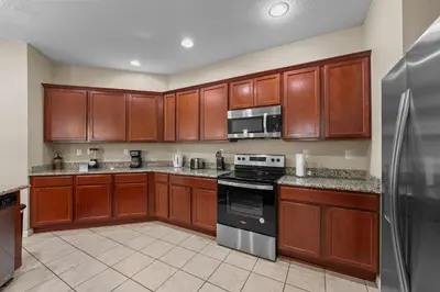 a kitchen with wooden cabinets and a stove top oven at 4 Bed Close to Disney Private Pool in Kissimmee