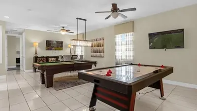 a living room with a pool table and a tv at Vila 7Q Temática c/ Piscina – 6mi Disney in Orlando