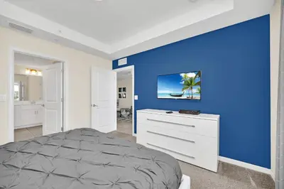 a bedroom with a blue accent wall and a bed at Ev4721C304 - Sunset Nest in Kissimmee