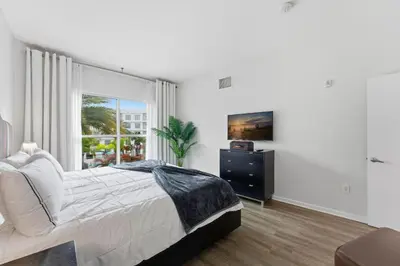 a white bedroom with a bed and a window at Orlando Getaway with Pool View Balcony in Orlando
