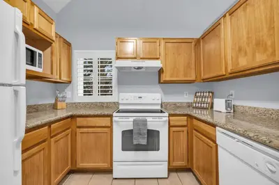 a kitchen with wooden cabinets and a white stove at Family Resort Condo Disney 5 miles in Kissimmee