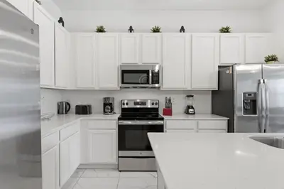 a kitchen with white cabinets and stainless steel appliances at Chic Modern Escape 12BR Pool and Game Room in Kissimmee