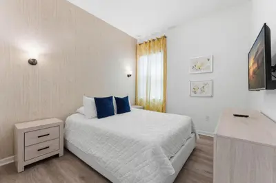 a white bedroom with a bed with blue pillows at Chic Modern Escape 12BR Pool and Game Room in Kissimmee