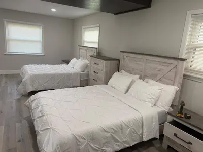 a bedroom with two beds and a dresser and two windows at Lakefront Luxury w Private Dock Sunrises in Orlando