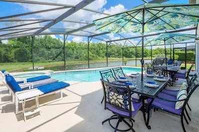 a patio with a table and chairs and a pool at Luxury 7BR w Pool Lake View at Berkley in Kissimmee