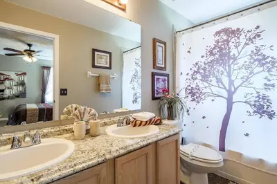 a bathroom with a sink and a toilet and a mirror at Luxury 7BR w Pool Lake View at Berkley in Kissimmee