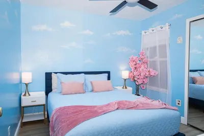 a bedroom with blue walls and a bed with pink pillows at 3BR Disney Home with Pool , Arcade and Hot Tub in Kissimmee