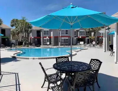 a table and chairs with an umbrella next to a pool at Condo Epic Universal Disney Free Parking in Orlando