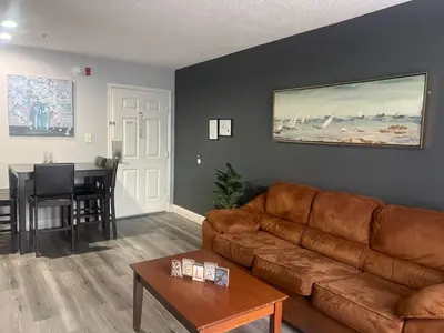 a living room with a brown leather couch and a table at Condo Epic Universal Disney Free Parking in Orlando
