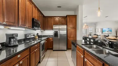 a kitchen with wooden cabinets and a stainless steel refrigerator at Upstay Great 3BR Condo w Scenic Views & Patio in Orlando