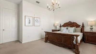 a bedroom with a wooden bed and a chandelier at Upstay Great 3BR Condo w Scenic Views & Patio in Orlando