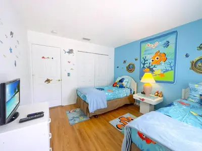a childs bedroom with two beds and a tv at Minutes from Disney Themed 2 Bd Villa with Private Pool home in Orlando