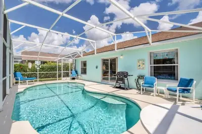 a swimming pool with blue chairs and a house at Minutes from Disney Themed 2 Bd Villa with Private Pool home in Orlando