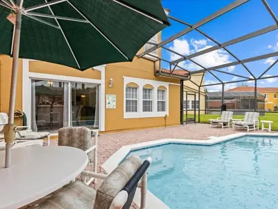 a pool with a table and chairs and an umbrella at 4bd Villa Near Epic Universe and Disney with private Pool townhouse in Kissimmee