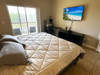a bedroom with a large bed and a flat screen tv at Very Near Disney 3 Bd Condo Walmart 1 min away townhouse in Orlando