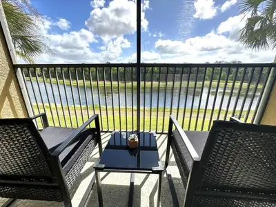 a balcony with two chairs and a table with a view of the water at Very Near Disney 3 Bd Condo Walmart 1 min away townhouse in Orlando