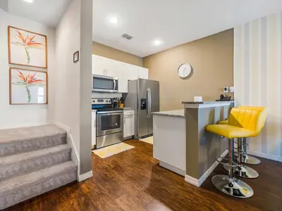 a kitchen with a counter and a bar with yellow chairs at Elegant Townhome at West Lucaya in Kissimmee