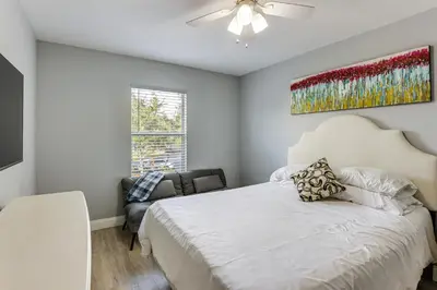 a bedroom with a white bed and a chair at 5 Mi to WDW! Spacious Resort Escape with Pool Access in Kissimmee